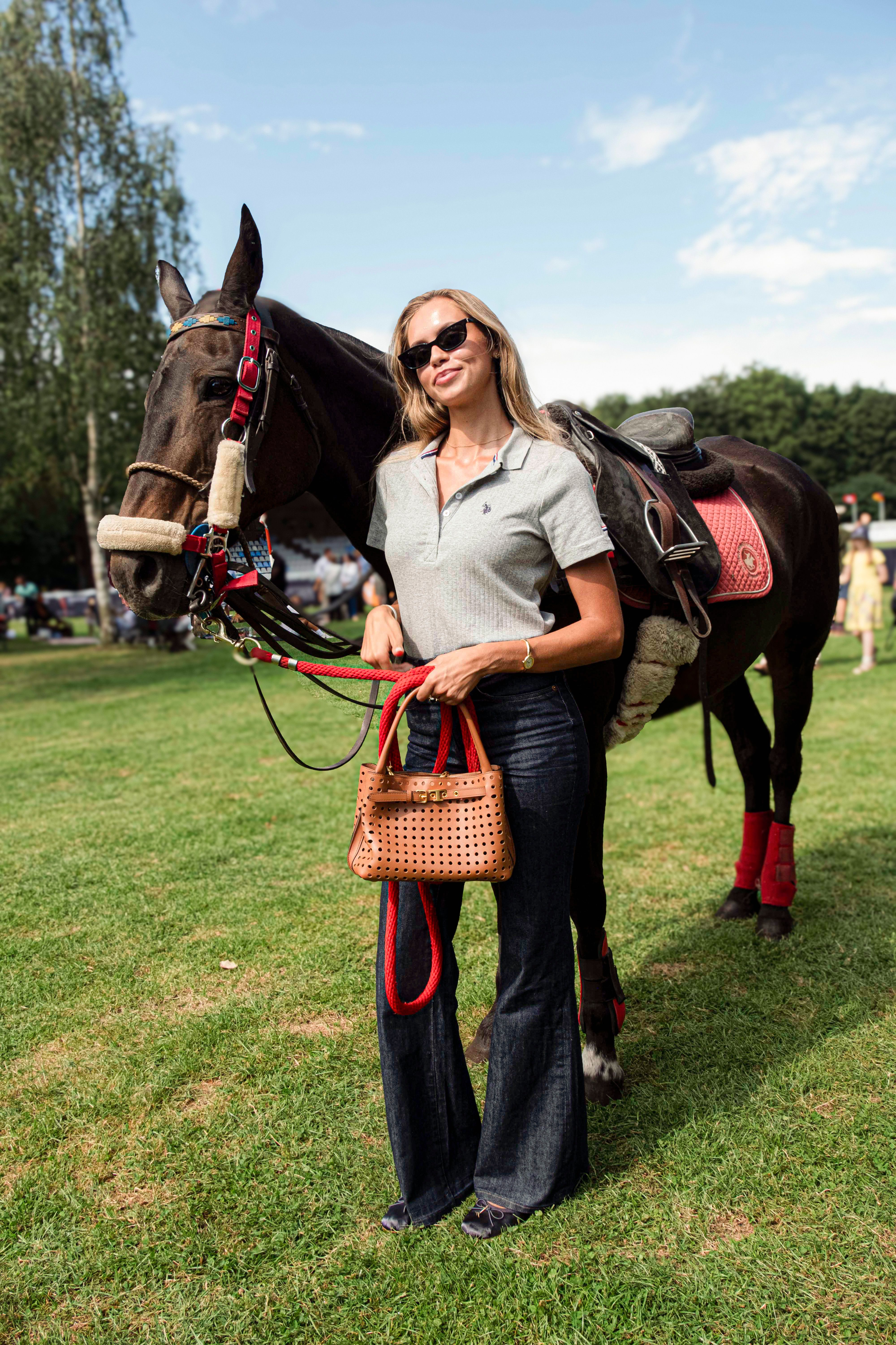 A guest posing with a polo horse at Polo in the Park