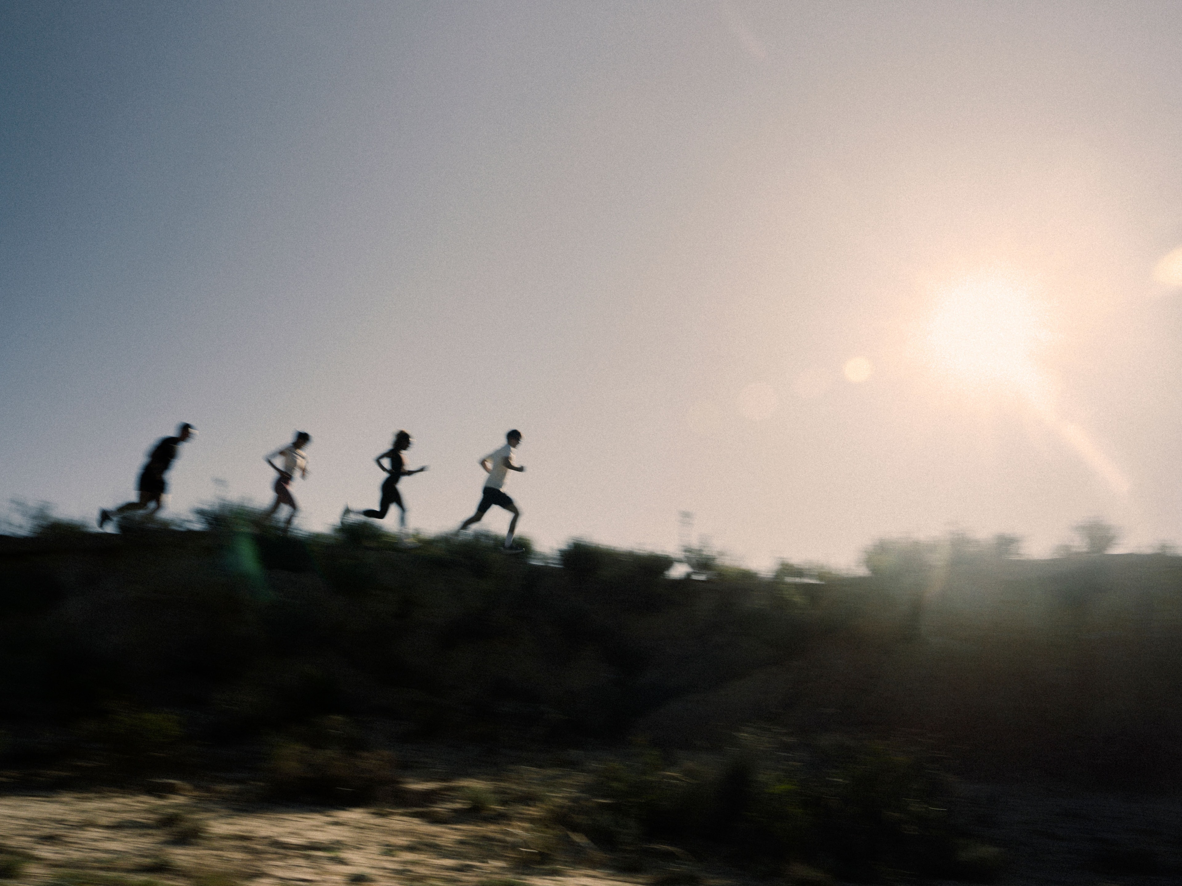 A group running along a sunlit ridge